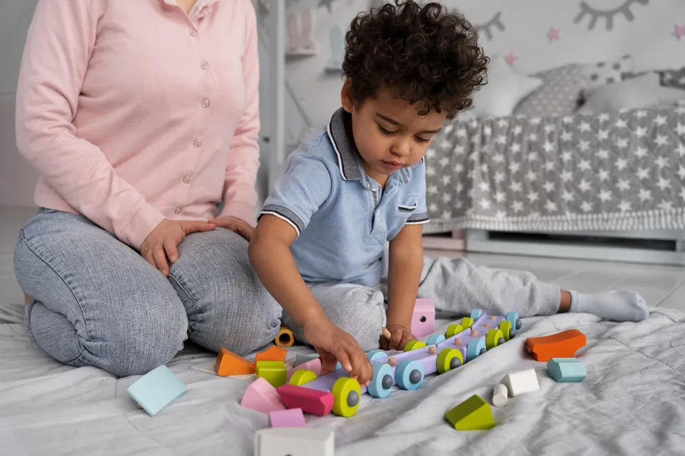 A child explores a colorful activity board alongside an adult.