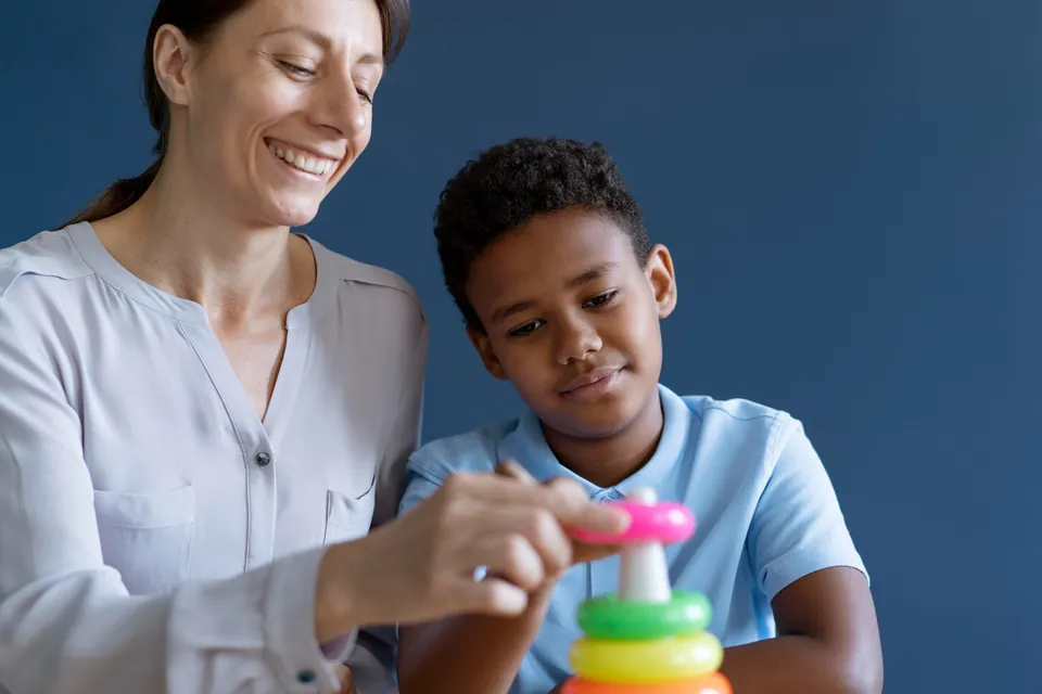 A child and an adult explore colorful stacking rings together.
